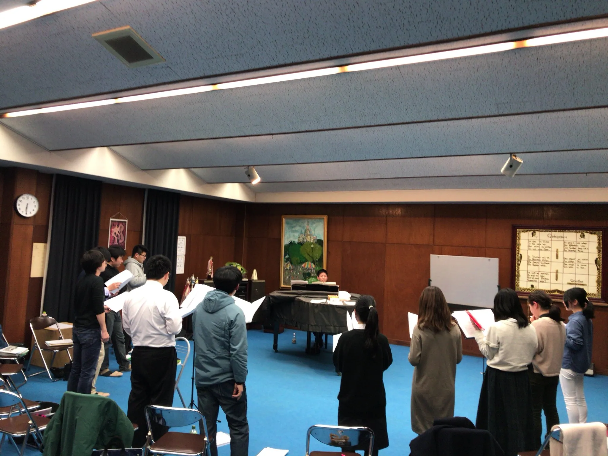 ホールでピアノを囲んで練習する団員たち