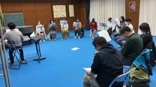 輪になって座り、楽譜を読む団員たち